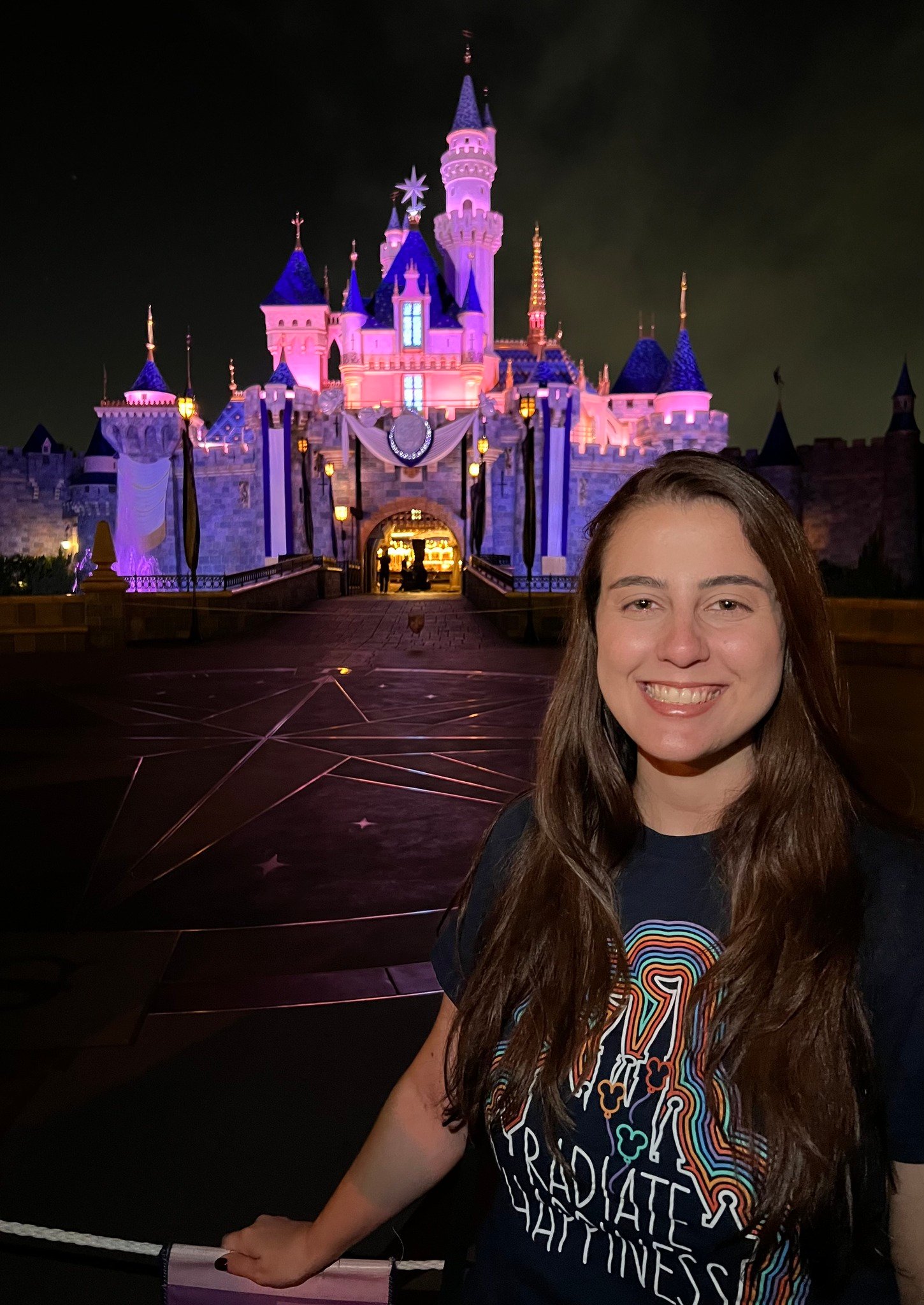 Camila, especialista em viagens, em frente ao castelo da Disneyland California iluminado a noite
